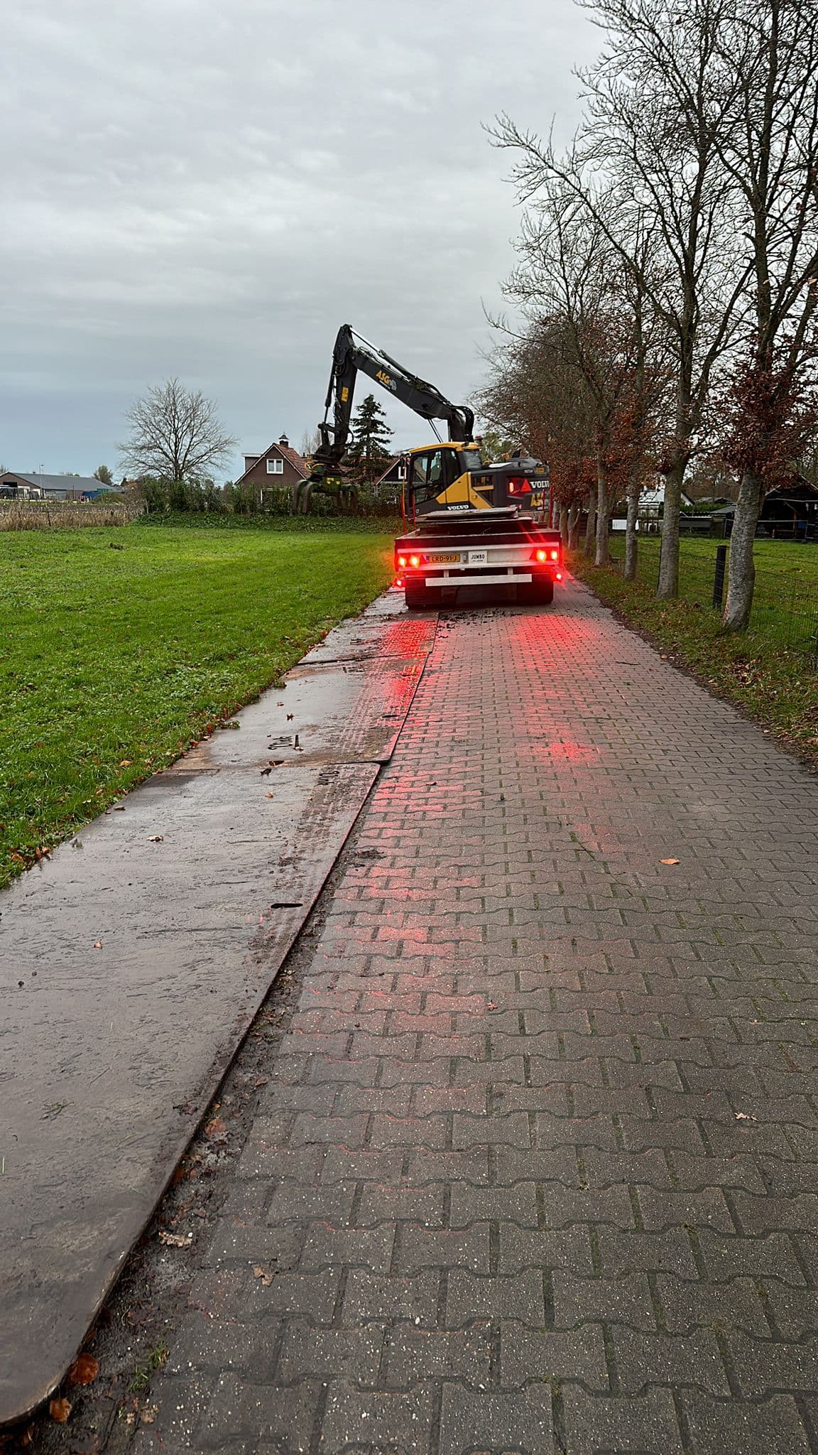 Kraan op transport gezien vanaf een natte klinkerweg