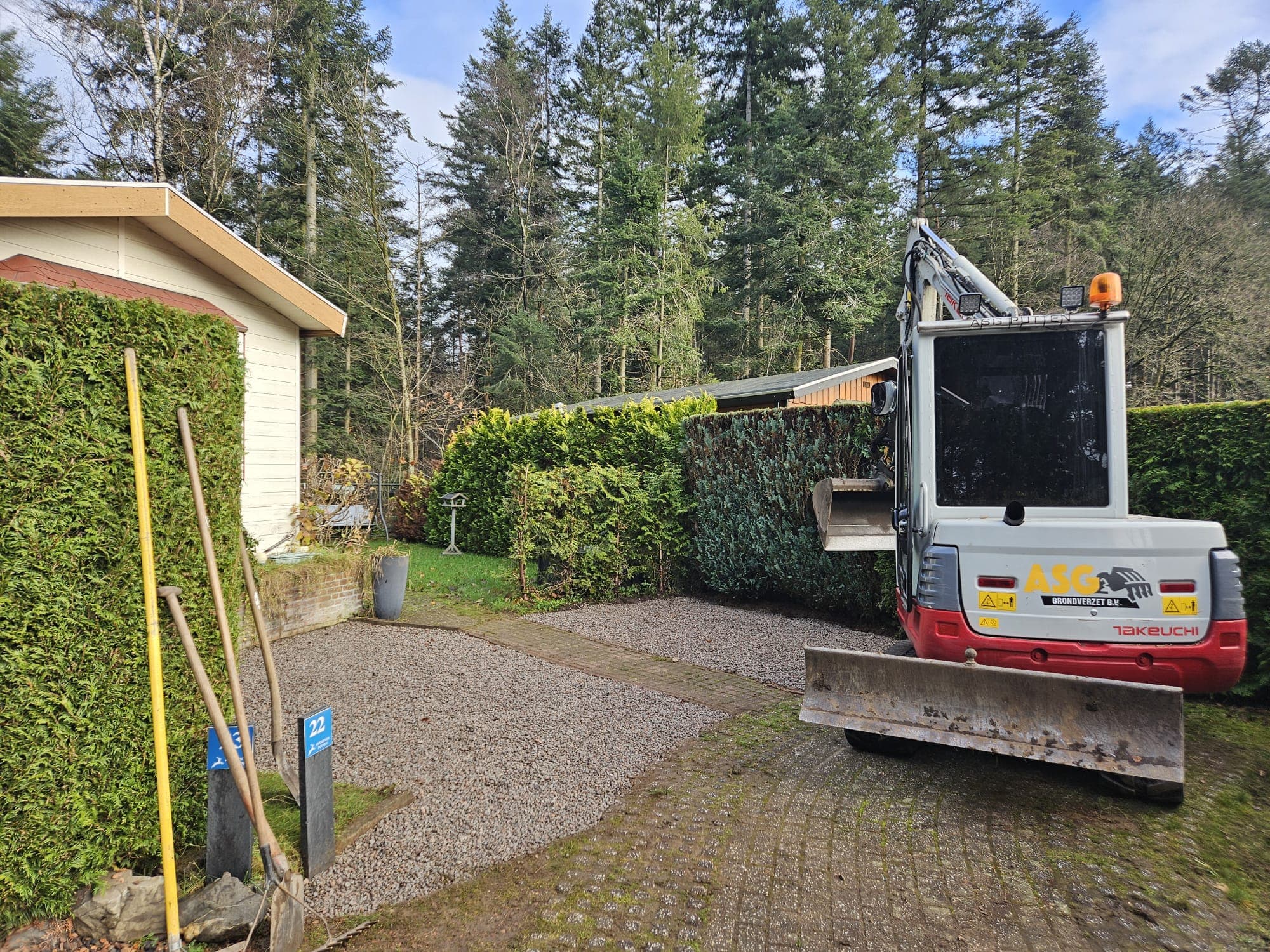 Minikraan op oprit bij grondwerk naast woning