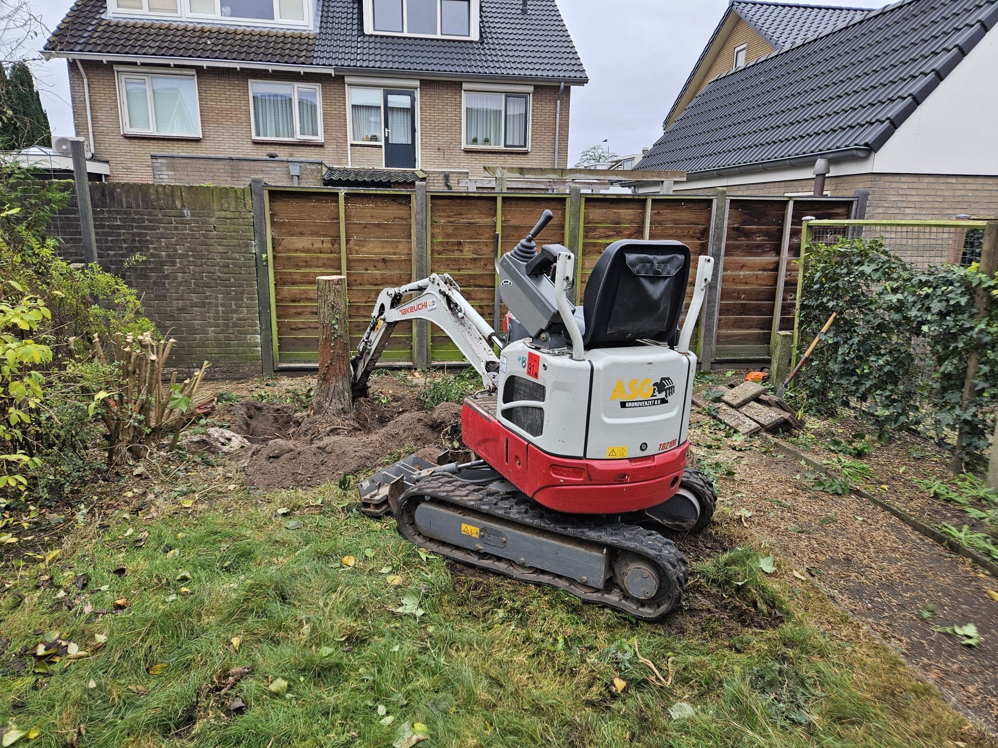 Minikraan verwijdert stobben in een tuin
